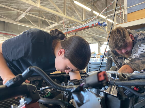 Bildunterschrift 1: Hoch konzentriert löst Schülerin Carla unter der Aufsicht von Kfz-Mechatroniker Luca alle Schrauben, um den kaputten Motor auszubauen. (Foto: Handwerkskammer Region Stuttgart)
